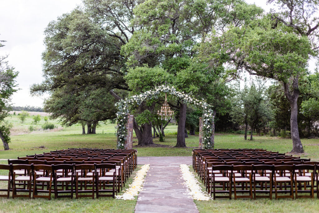 Romantic wedding design with floral archway and rustic chairs at Ma Maison venue