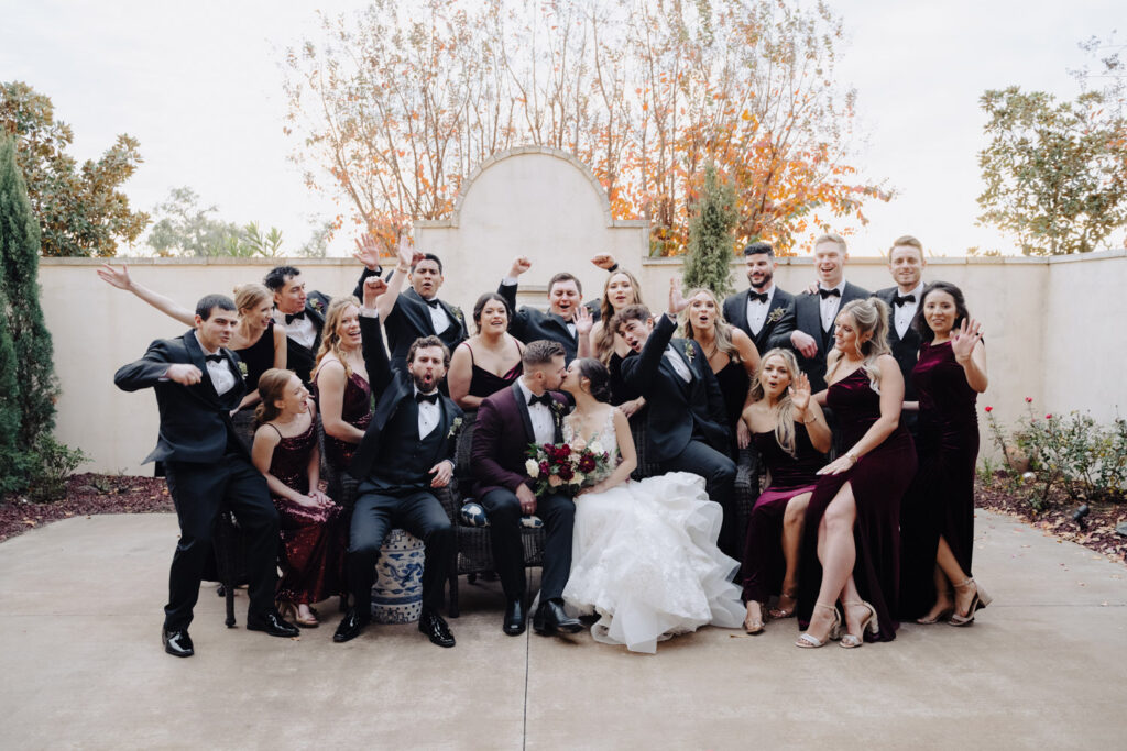 Energetic bridal party cheering as newlyweds kiss