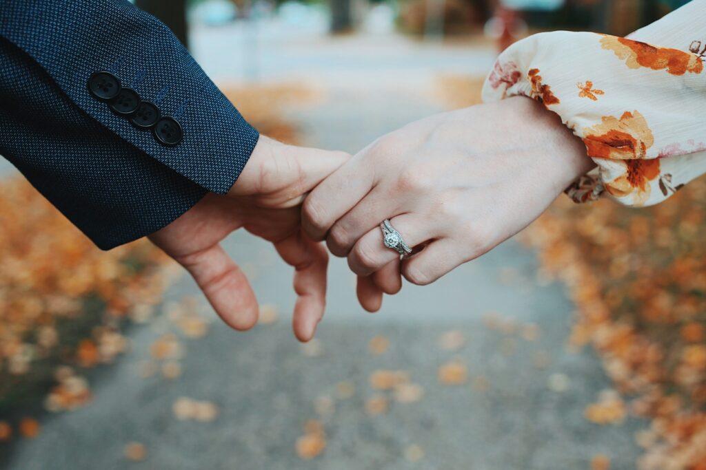 man and woman holding hands showcasing the engagement ring fall themed