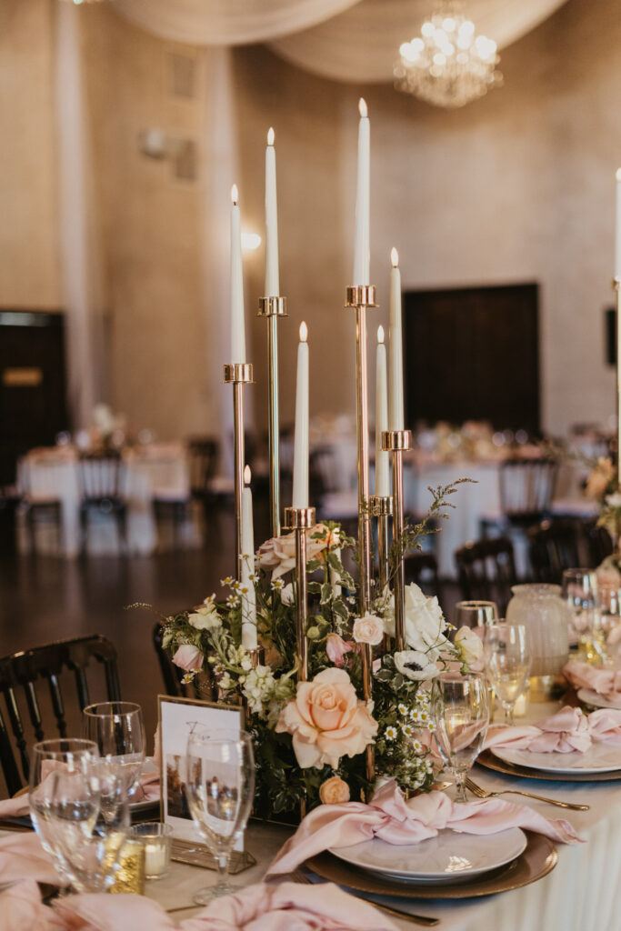 Tall taper candle centerpiece with delicate florals showing hard-to-transport worst wedding flowers