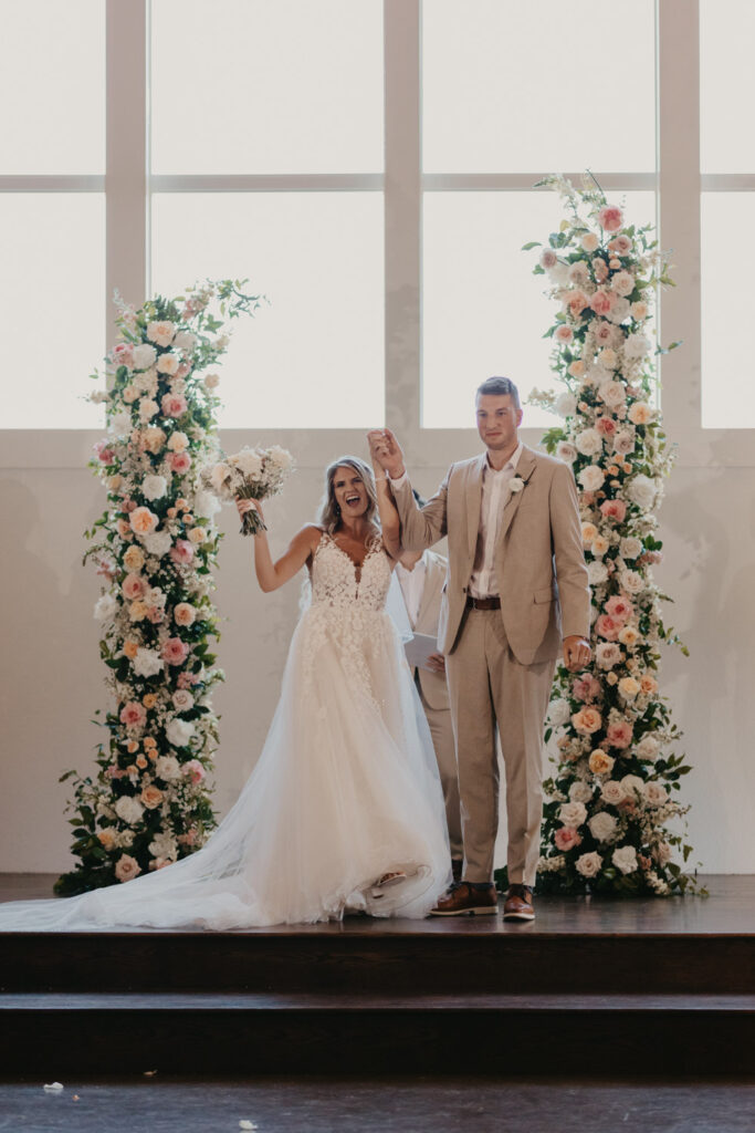 Bride and groom celebrating with floral pillars that use tricky stems